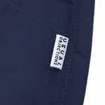 Close-up of navy blue fabric with a small white fabric label reading 'USUAL OBJECTIONS' stitched onto it.