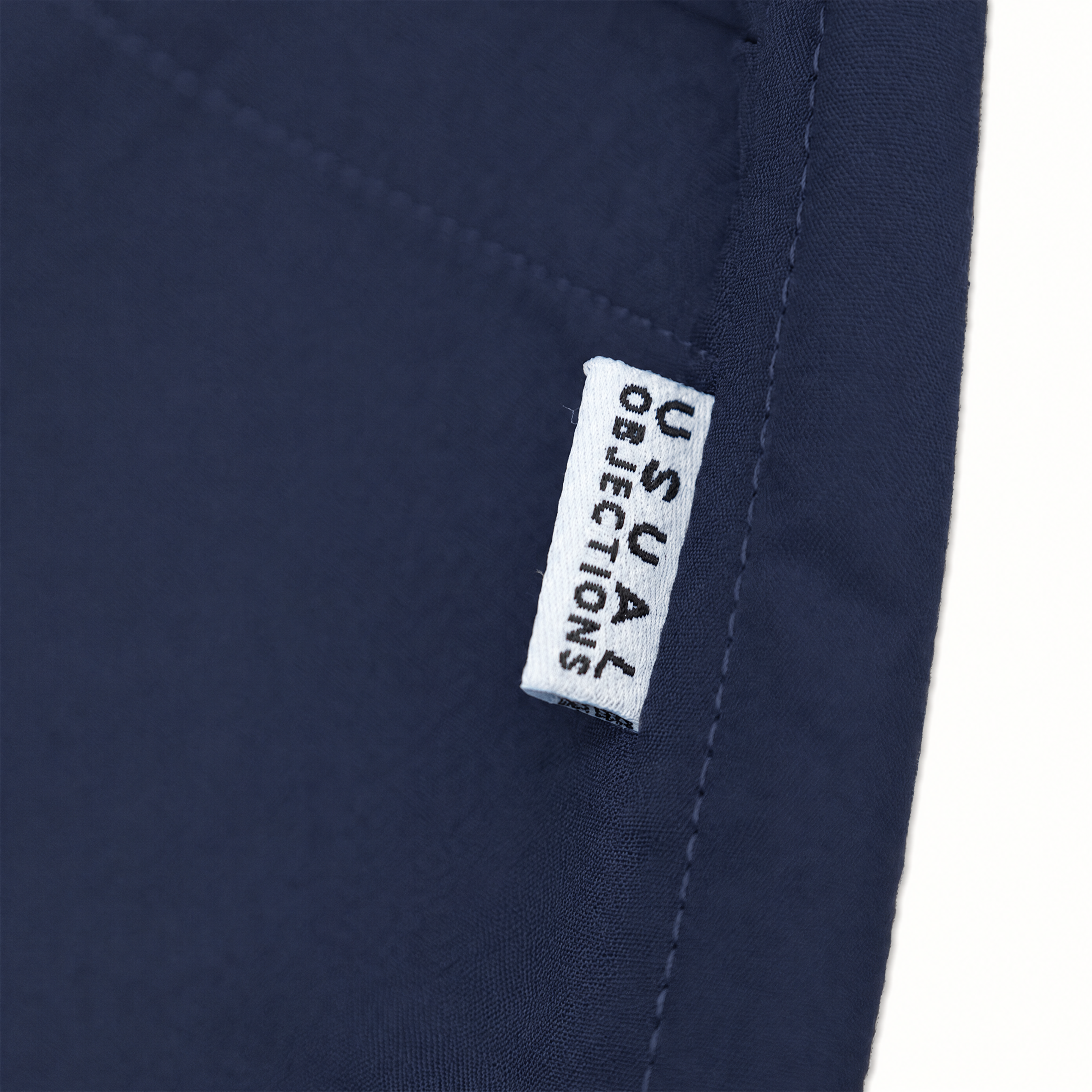 Close-up of navy blue fabric with a small white fabric label reading 'USUAL OBJECTIONS' stitched onto it.